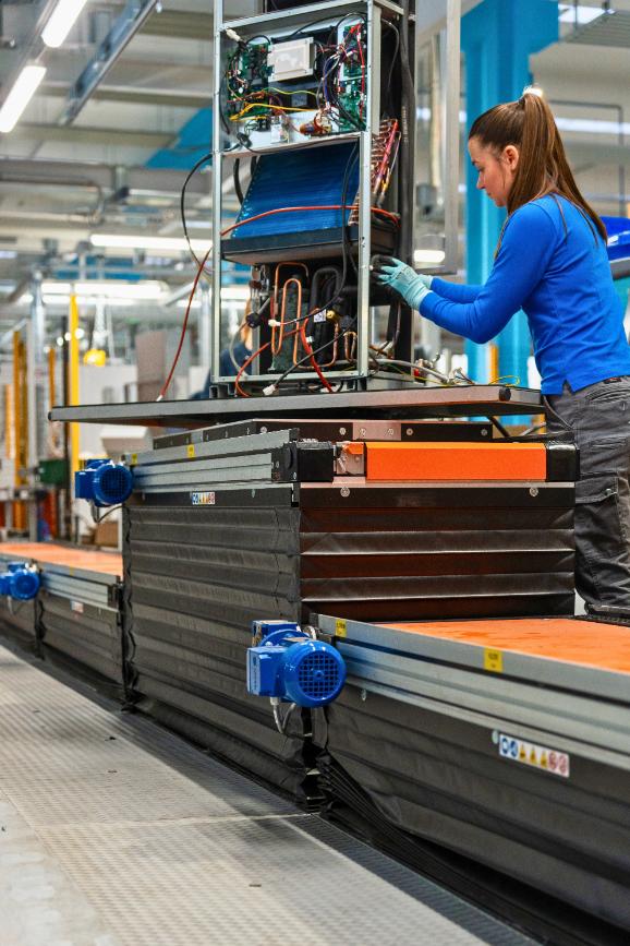 Operatore di linea mentre lavora su una stazione di assembly con una piattaforma elevatrice a forbice (Scissor lifting table) integrata nella linea di produzione realizzata da Movin per la produzione di prodotti del settore HVAC