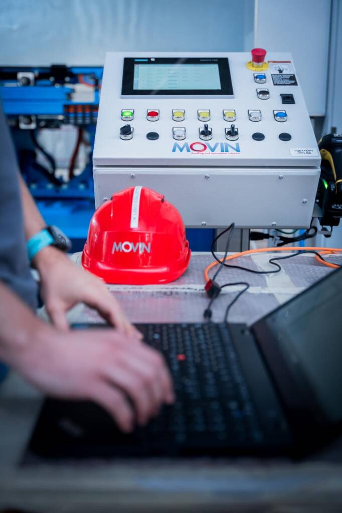 Sviluppatore software Movin che programma il plc di un system di assembly con i dispositivi di sicurezza dpi Movin che garantiscono la necessaria sicurezza per procedere al testing dellu2019system