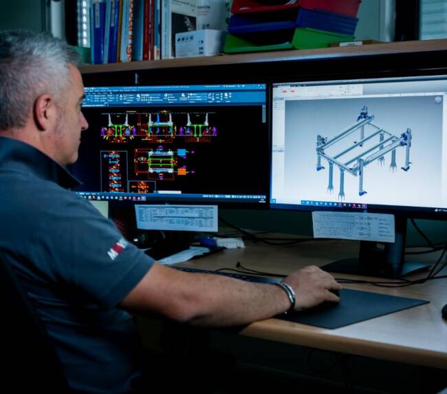 Ingegnere meccatronico Movin mentre progetta in 3D dei manipolatori automatici utilizzati in una line di assembly per banchi frigo