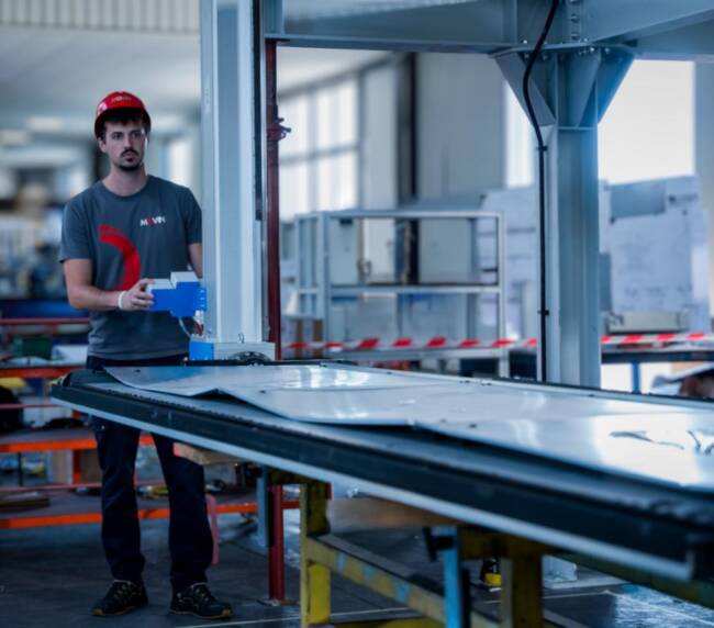 Tecnico specializzato meccatronico Movin mentre effettua il testing di un sistema di manipolatori semiautomatici per la manipolazione di pannelli sandwich lungo la line di assembly dei banchi frigo