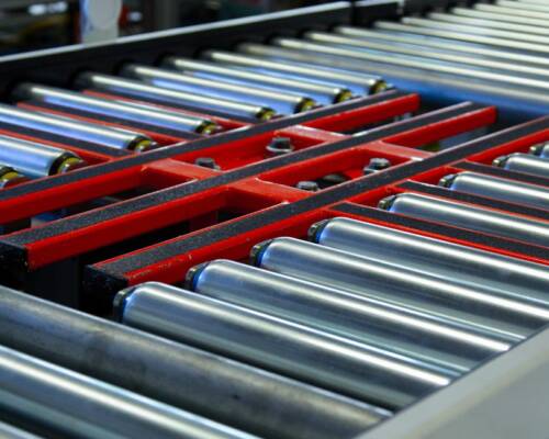 trasferitore su un nastro trasportatore a rulli motorizzati lungo una linea di assemblaggio realizzata da Movin per la produzione di frigoriferi ed elettrodomestici
