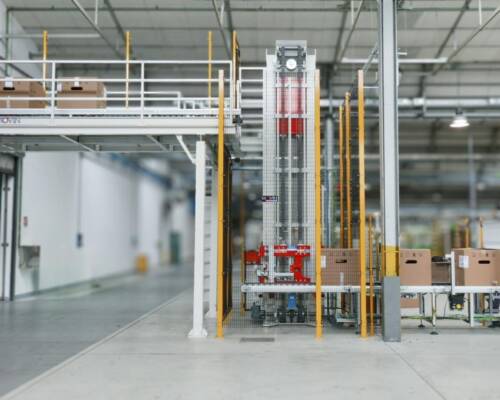 Elettrodomestici a fine linea imballati che vengono trasferiti tramite un elevatore dallo stabilimento produttivo al magazzino prodotti finiti per lo stoccaggio